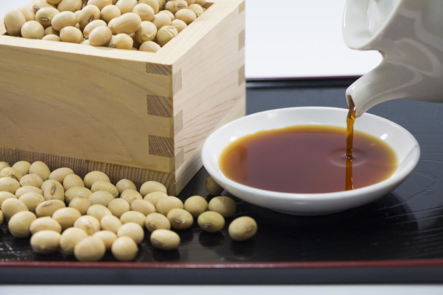 桝に入った大豆と注がれる醤油